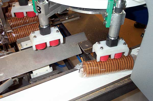 Slugs of Ginger Nuts in clear, cold-seal film move from rotary wheel transfer.