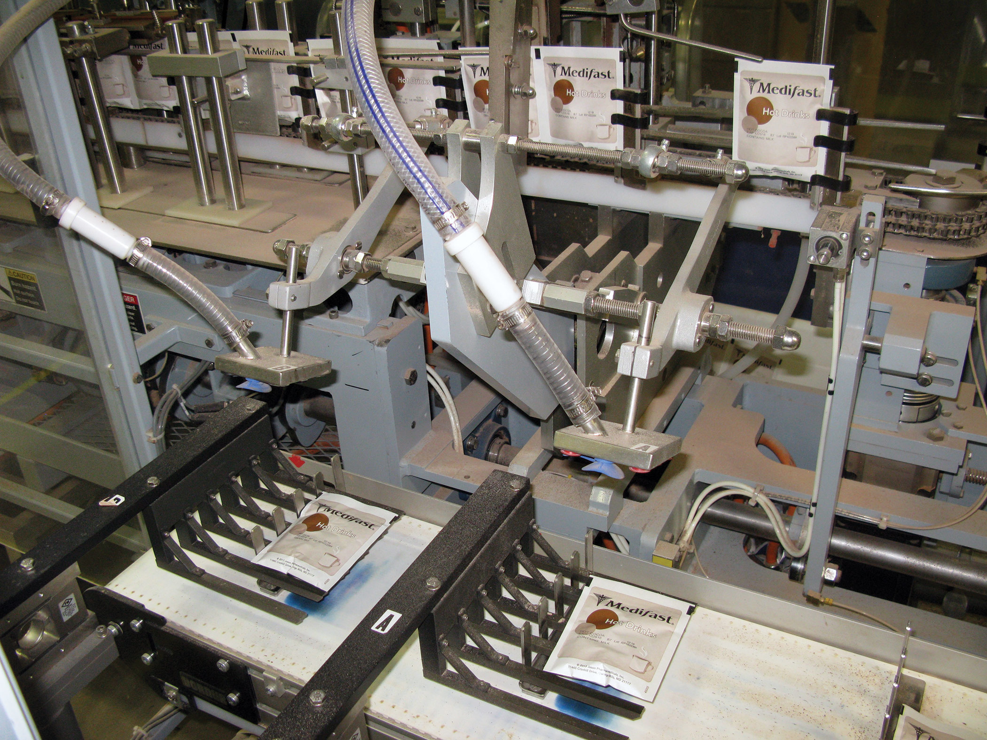 Once pouches are cut into individual units, a pick-and-place device puts each pouch on a pedestal checkweigher.
