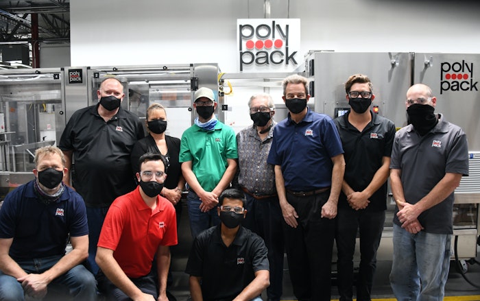 Surrounded by employees Alain Cerf (President and CEO of Polypack) stands proudly next to a recently finished machine.