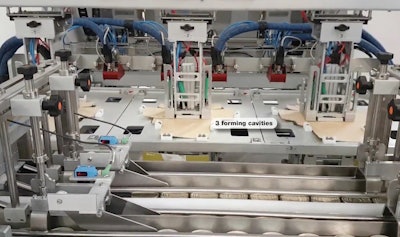 Seen here are three carton forming cavities and, in the foreground, cans that will be top-loaded into the cartons.