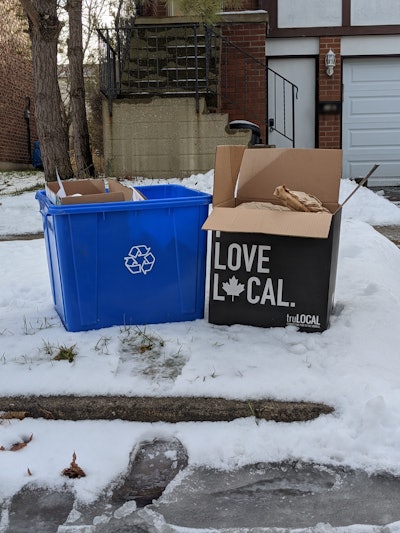 The secondary packaging system is curb-side recyclable in any municipality that uses full curb-side recycling. It consists of a printed corrugated outer box, paper insulation to allow dry ice packets to keep temperature, and a recyclable (in Alberta and BC; material not specified) bag to keep the corrugated and insulation from getting soggy due to any condensation in transit.