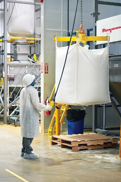 A cantilevered I-beam with hoist and trolley allows bags to be raised and rolled into a discharger using a pendant.