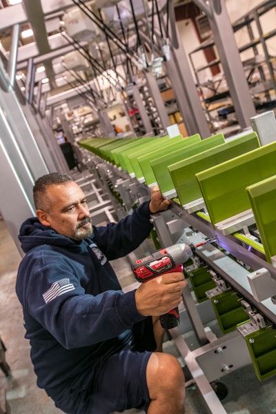 Aurelio Lara, a mechanical assembly tech, works on the product bucket conveyor for a cartoner.