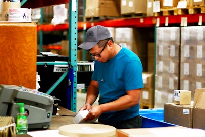 Cong Nghiem, Warehouse Specialist, unboxing an incoming package.