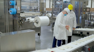 Operators at Golden State Foods inspect condiment-filled pouches coming off the vf/f/s line, ready for secondary packaging.