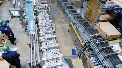 Infeed of 5-oz and 7-oz canned and glue-applied labeled product into the cartoner at the Santa Fe, Calif. Bumble Bee facility. Note the layout of three parallel tracks, with product first entering the space and feeding the cartoner on the center track. After product is cartoned and laned, it turns sharply 180 deg, carrying product downstream while parallel to the cartoner. Product then takes another, wider 180-deg turn around the cartoner, and finally travels parallel to the previous two tracks again for tray packing.