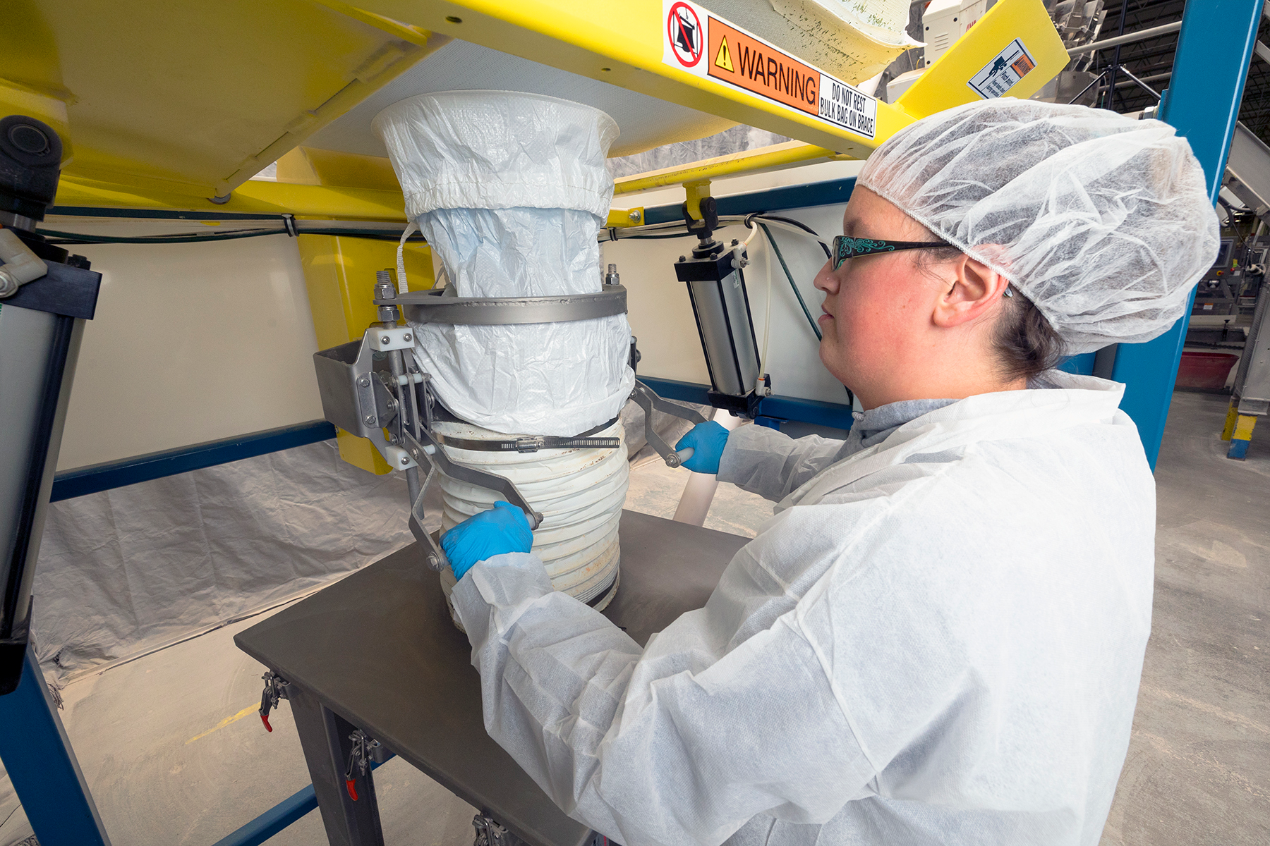 An operator connects the bag spout to the system&rsquo;s clamp ring and telescoping tube, which maintains constant downward pressure on the bag as it empties and elongates, promoting flow.