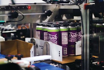 Pairs of labeled 6-pack multipacks with PakTech can handles applied are packed in high-walled 12-count trays on DMM equipment.