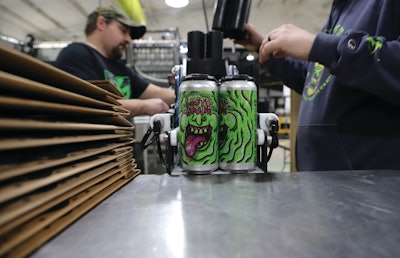 After PakTech can handles are applied to labeled cans, operators pack cans into pop-up trays in a pack-off station that ends the contiguous line.