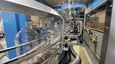 Blown bottles exit the blow molder on Dyco conveyers.