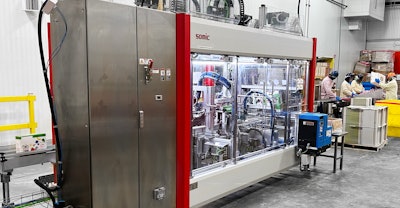 Upstream operators feed the casepacker from totes filled with pouches that have gone through HPP.