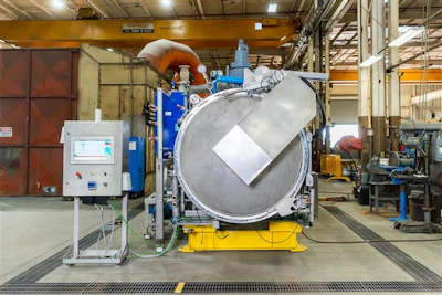 Large industrial autoclave or pressure vessel with control panel in manufacturing facility
