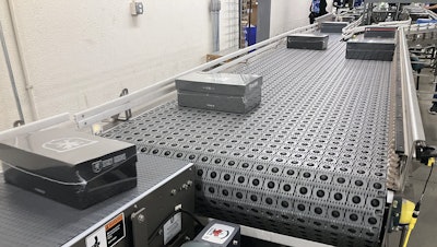 As boxes are discharged from the shrink wrapper on the black plastic belting shown here, they enter another ARB conveyor that diverts them to one of two lines leading to automated labeling systems.