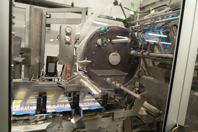 Orbi-track carton feeder puts erected cartons into position so that bags of product can be pushed into cartons.