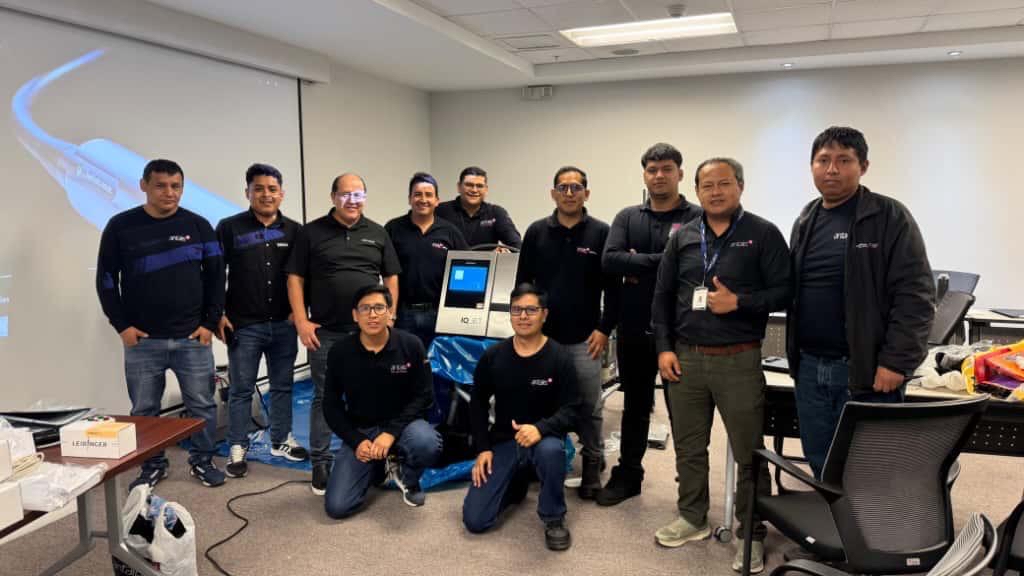 Tech team of 11 professionals posing together in an office meeting room