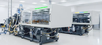 Industrial injection molding machines in a clean manufacturing facility with white walls and overhead lighting
