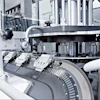 The oval-shaped linear track of the Beckhoff XTS is tilted by 45 degrees relative to the plane on which pucks deliver bottles to a capping station.