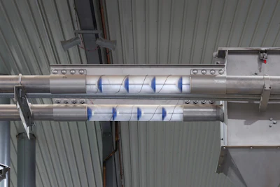 Industrial dual-shaft conveyor system with blue directional markings mounted in warehouse facility