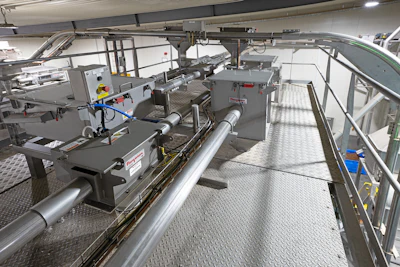 Industrial manufacturing facility with machinery, workstations, and metal flooring in a warehouse setting