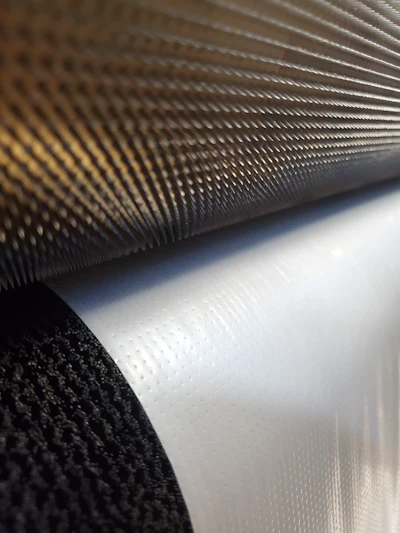 A close-up of nipped material between a pinned micro-perforating roller and a brush roller.