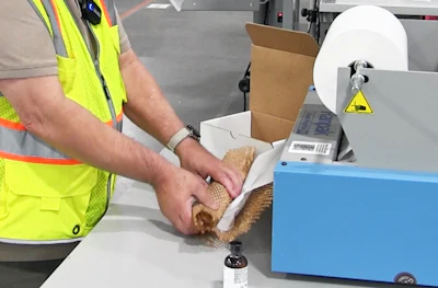 A Ranpak dispenser expands die-cut kraft into a honeycomb structure with a tissue interleaf, replacing bubble wrap and, in many orders, an inner carton.