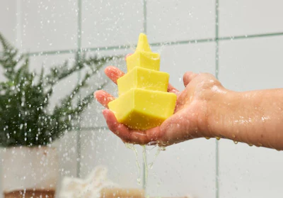Yellow rubber duck held under running water in a bathroom shower