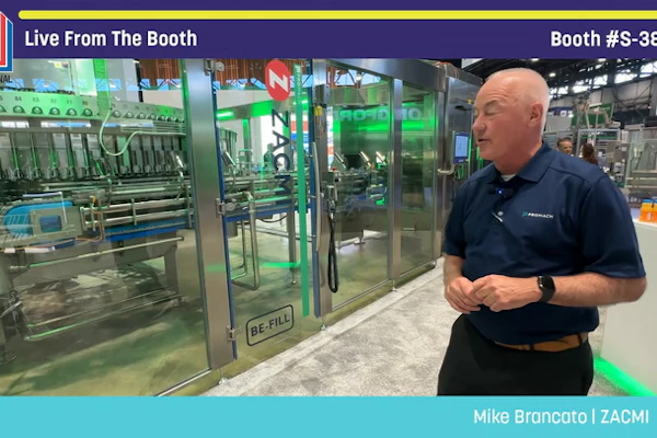 Man in navy polo shirt presenting industrial packaging equipment at PACK EXPO booth S-3847