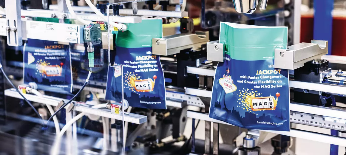 Industrial packaging equipment displaying MAG Series branded boxes in turquoise and navy with gold accents in a manufacturing facility