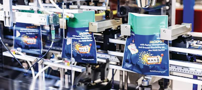 Industrial packaging equipment displaying MAG Series branded boxes in turquoise and navy with gold accents in a manufacturing facility