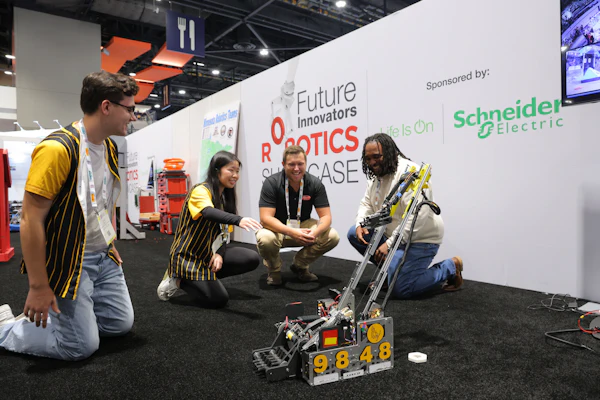 Team members demonstrate a yellow and black robot at the Future Innovators Robotics Showcase, sponsored by Schneider Electric.