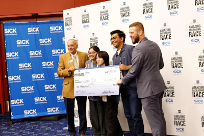 Team members and executives present oversized check at corporate awards event with SICK and Amazing Packaging Race branding