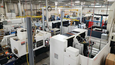 Industrial manufacturing facility with white CNC machines and equipment on factory floor
